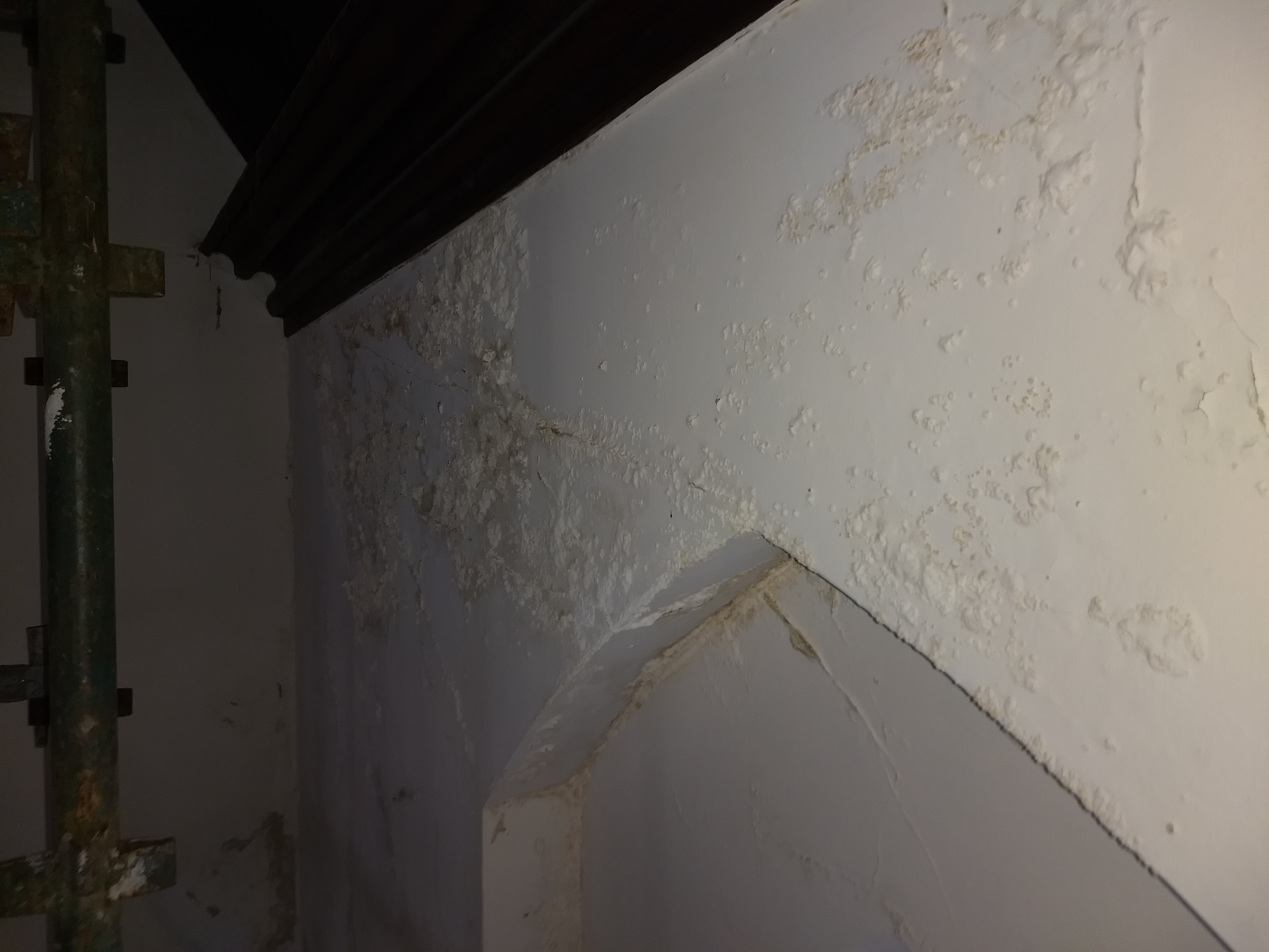 Water damaged church wall with blistered plaster before restoration